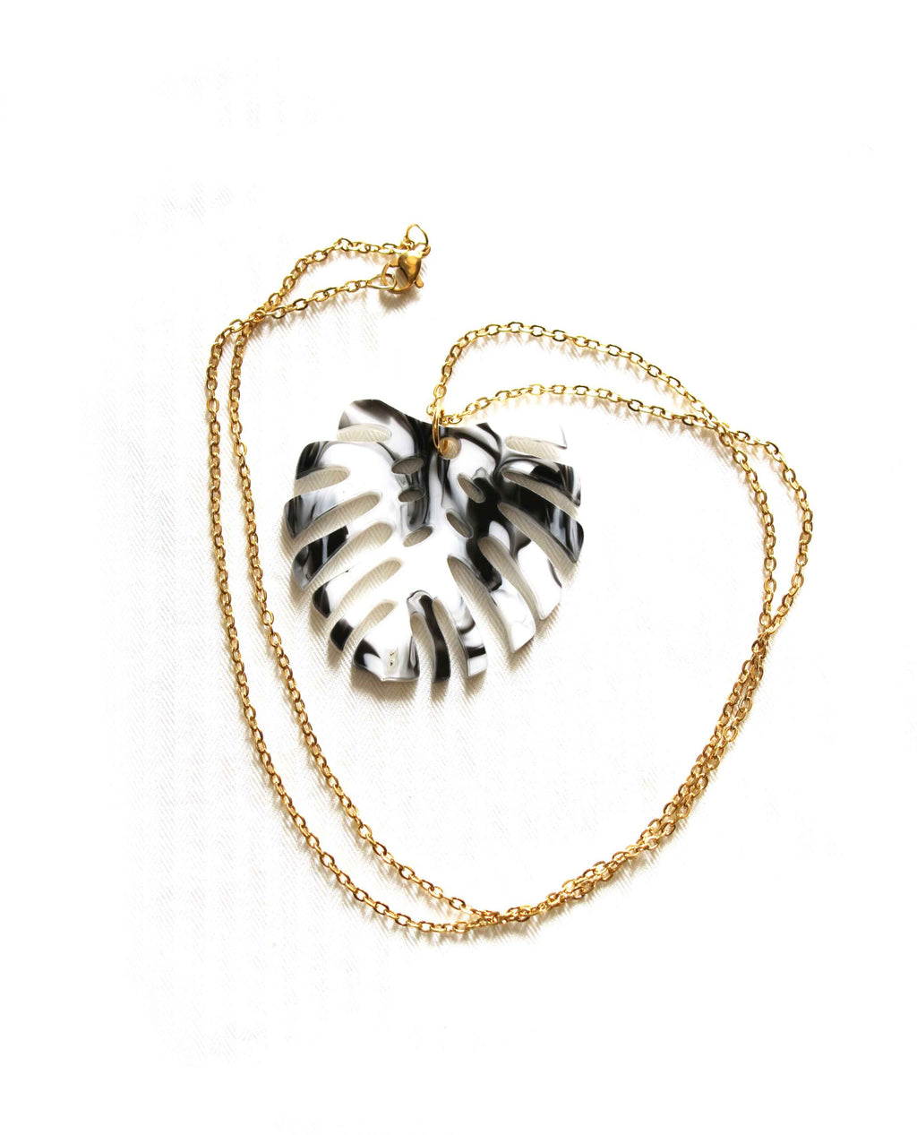 Collar dorado hoja monstera en blanco y negro