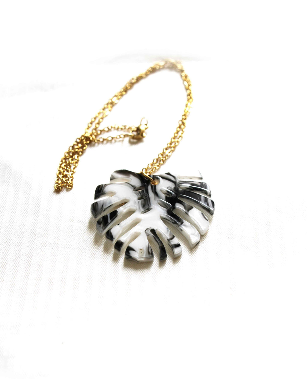 Collar dorado hoja monstera en blanco y negro