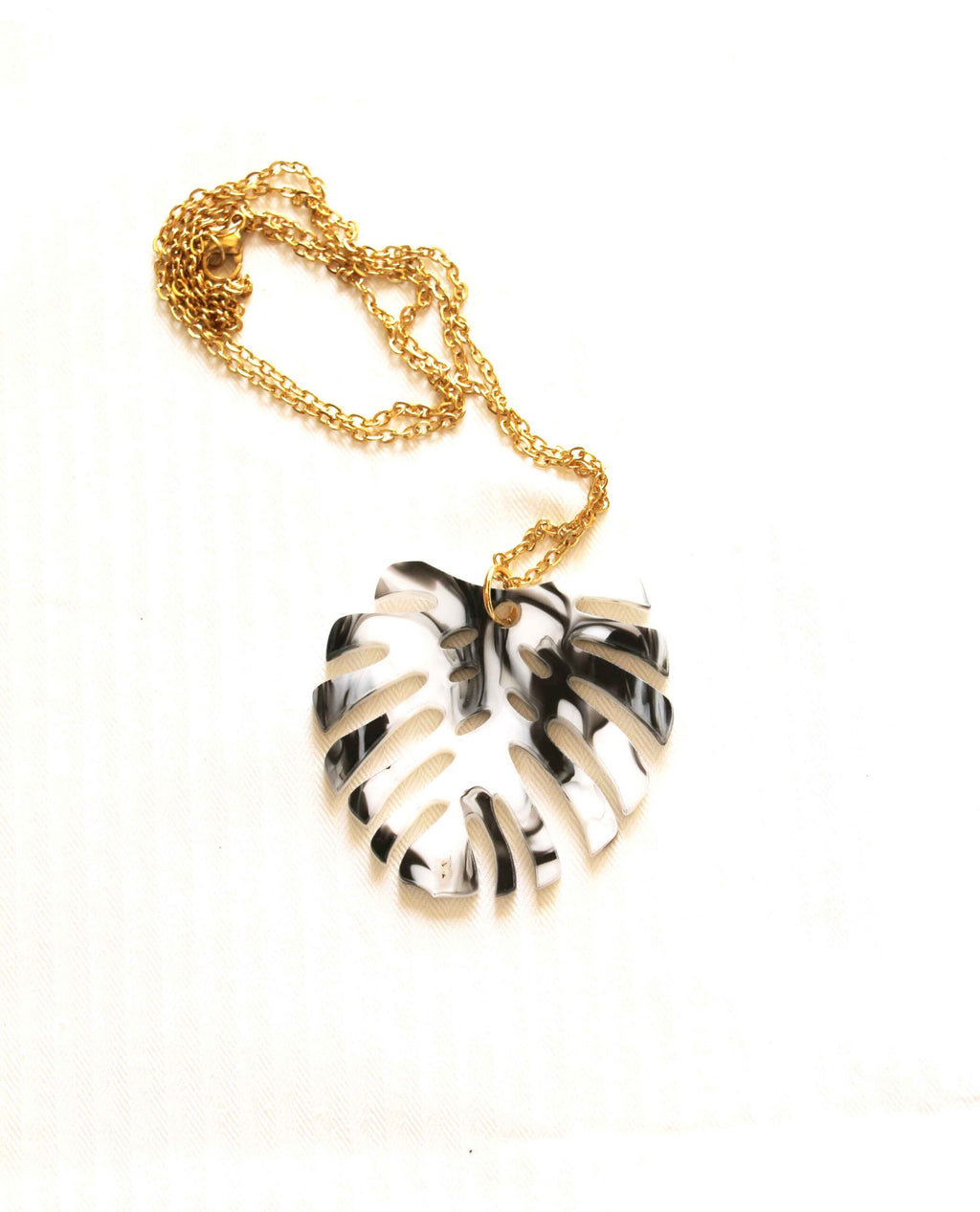 Collar dorado hoja monstera en blanco y negro