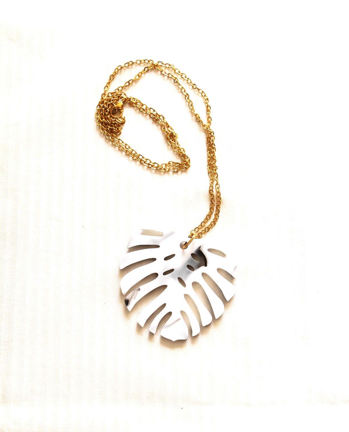 Collar dorado hoja monstera en blanco y negro