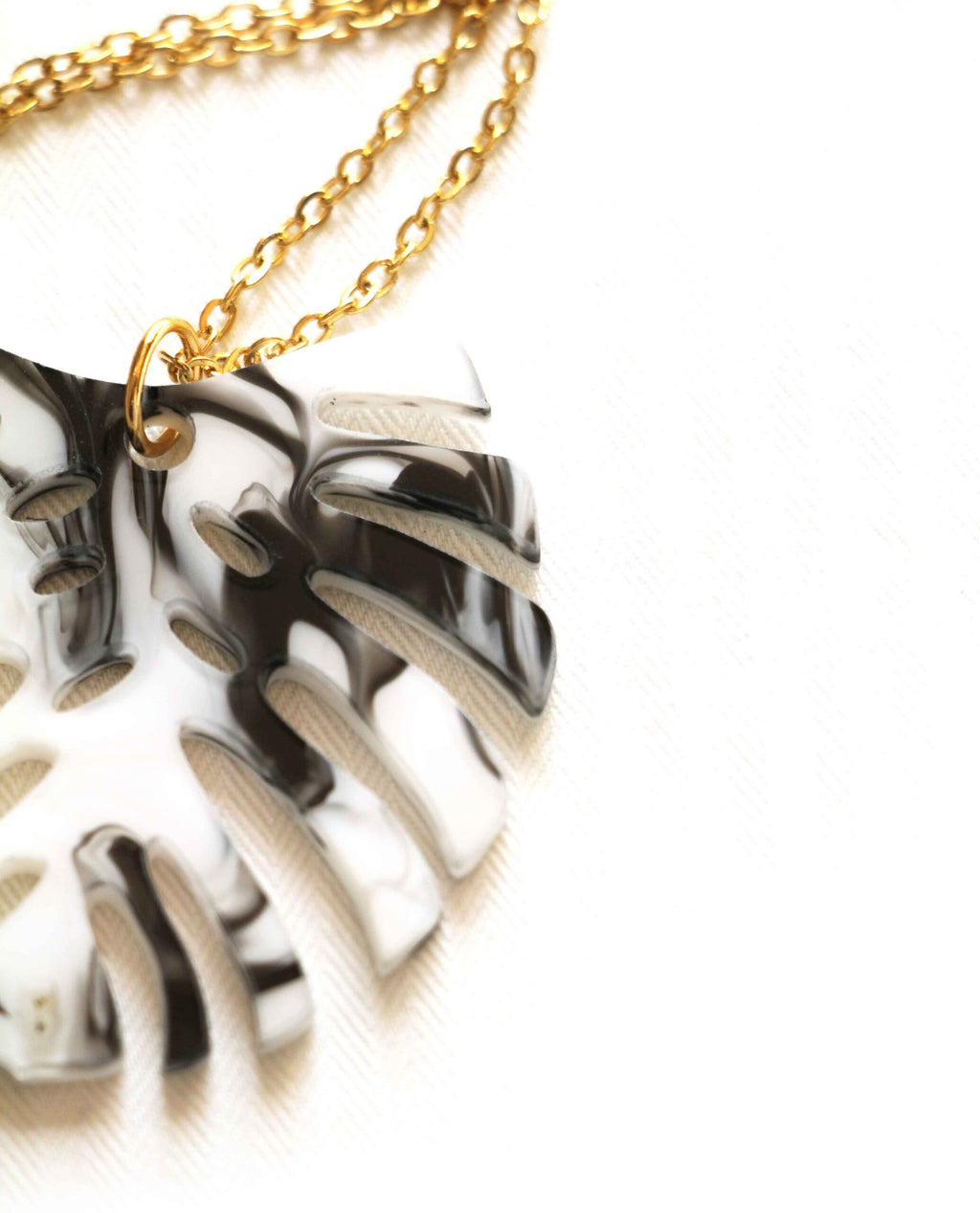 Collar dorado hoja monstera en blanco y negro
