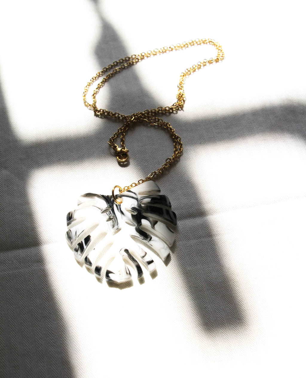 Collar dorado hoja monstera en blanco y negro
